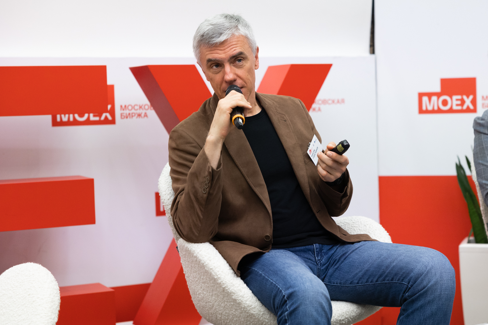 Спикер с микрофоном и кликером во время выступления на конференции Московской биржи.