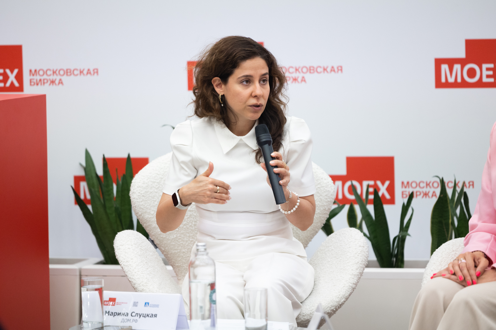 Женщина выступает с микрофоном на панельной сессии Московской биржи.