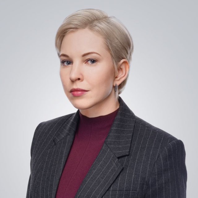 Женщина с короткой стрижкой в деловом костюме на светлом фоне, эксперт по архитектуре