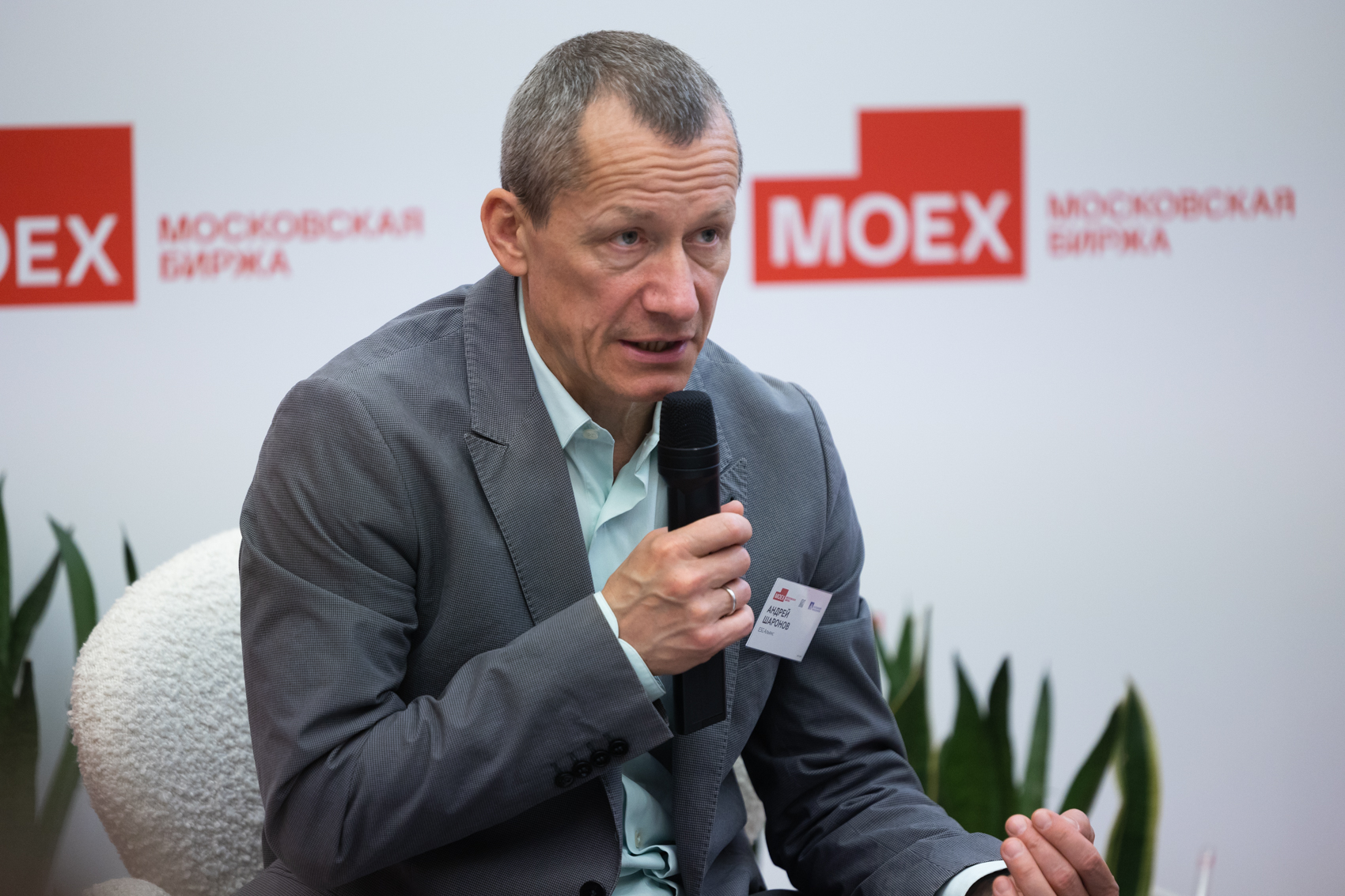 Участник дискуссии с микрофоном на мероприятии Московской биржи.